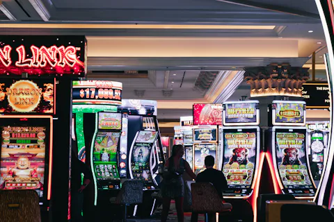 Players sitting at rows of brightly lit slot machines on a casino floor