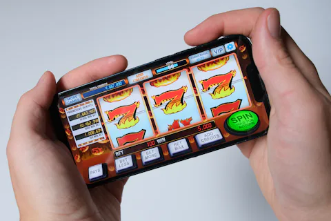 Hands holding a smartphone showing a classic 777 slot machine game