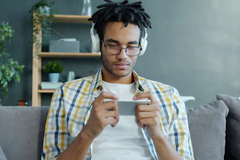 Young man relaxing on a sofa while playing a game on his smartphone