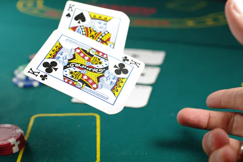 A player revealing playing cards above a green poker table