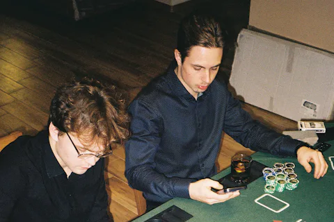 Two men concentrating during a game of poker at a green felt table