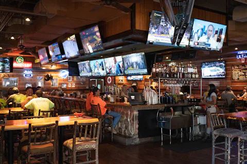 Fans watching live sports on several large TV screens in a busy sports bar